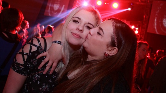 Zwei junge Frauen küssen sich freundschaftlich.