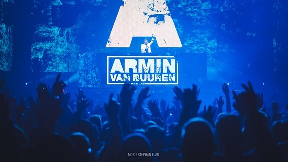 Armin van Buuren auf der Bühne - im Vordergrund Menschenmassen.