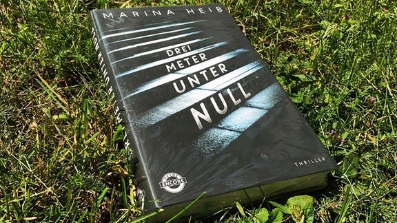 Das Buch "Drei Meter unter Null" von Marina Heib liegt im Gras.