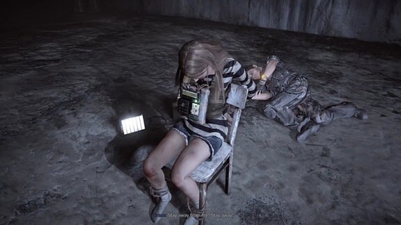 Eine Szene aus dem Computerspiel Get Even. Eine Frau sitzt auf einem Stuhl gefesselt und hat eine Bombe um den Hals. Hinter ihr liegt ein Mann. Auf dem Boden ist ein Laptop