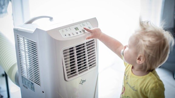 Kleinkind bedient eine Klimaanlage.