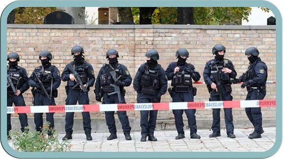 Polizisten in Vollschutz vor der jüdischen Friedhosmauer in Halle