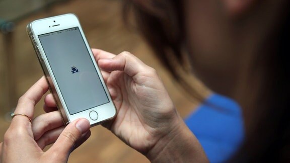 Blick über die Schulter einer jungen Frau auf ein Handy. Auf dem Display ist das Logo der App Once erkennbar.