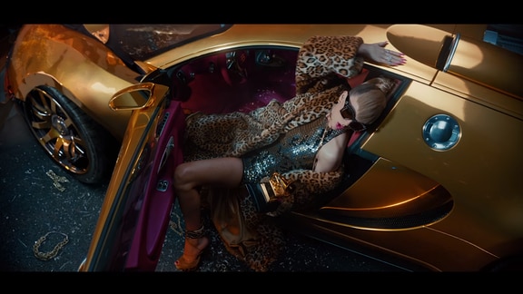 Taylor Swift sitzt in einem goldenen Auto