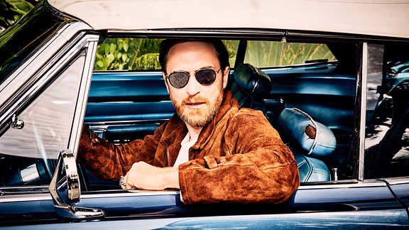David Guetta sitz in einem Cabrio mit geschlossenem Verdeck