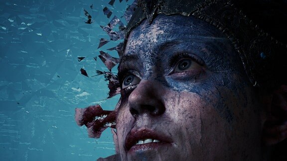Die Heldin des Computerspiels Hellblade. Die obere Gesichtshälfte ist mit dunkler, verkrusteter Farbe bemalt.