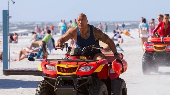Dwayne Johnson fährt Quad am Strand (Filmszene)