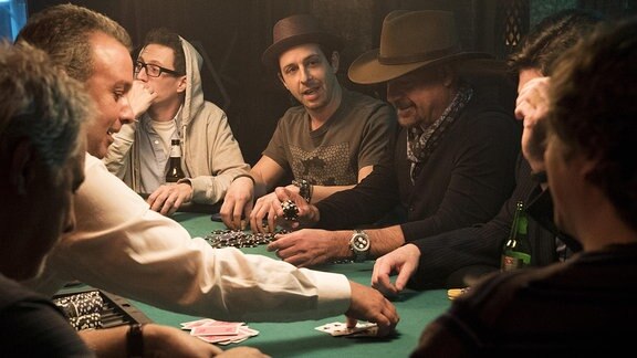 Männer spielen an eine Tisch Poker, Spielchips liegen vor ihnenFilmszene aus "Molly's Game"