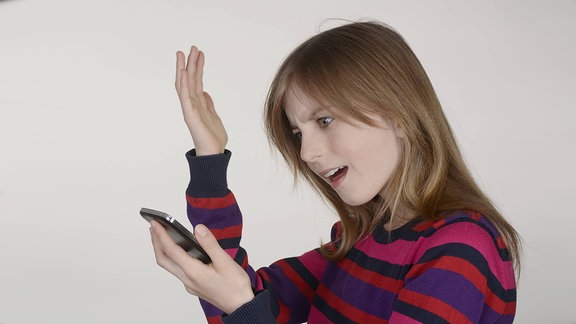Mädchen blickt fassungslos auf ihr Smartphone 