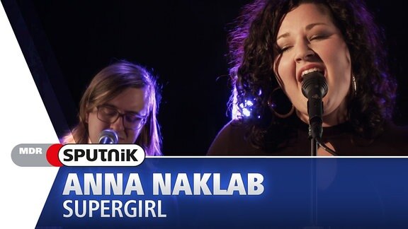 Anna Naklab singt ihren Hit "Supergirl" im SPUTNIK Videostudio. Im Hintergrund ist eine Begleitmusikern zu sehen.